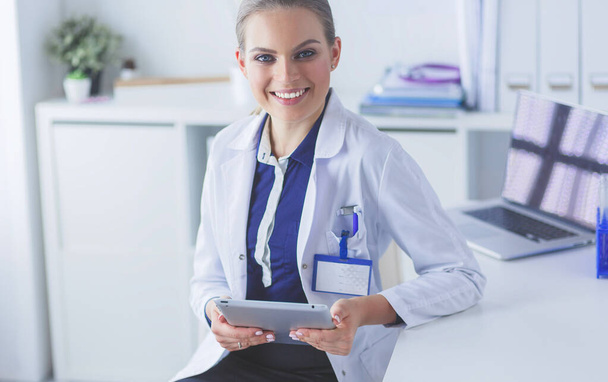Portrait of woman doctor at hospital corridor, holding tablet computer, looking at camera, smiling - Fotoğraf, Görsel