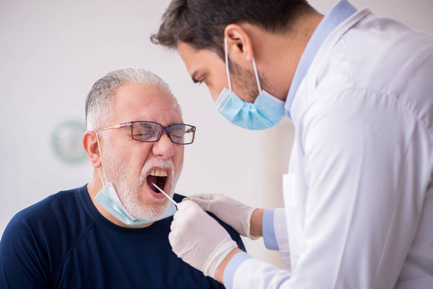 Paciente do sexo masculino velho visitando jovem médico otorrinolaringologista - Foto, Imagem