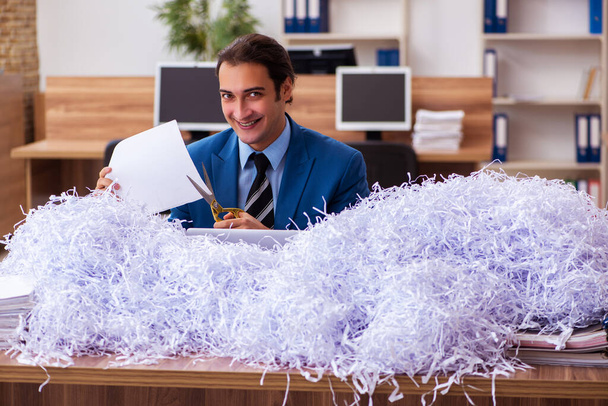 Jonge mannelijke werknemer en veel gesneden papieren in het kantoor - Foto, afbeelding