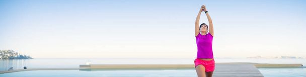 Γυναίκα προπονείται γιόγκα μπροστά στην πισίνα. Yoga θέτει σε εξωτερικούς χώρους μπροστά στη θάλασσα. Γιόγκα έξω. Κορίτσι κάνει πρωινή άσκηση μπροστά από την πισίνα στον Ειρηνικό Ωκεανό. Υγιεινή ζωή έννοια - Φωτογραφία, εικόνα