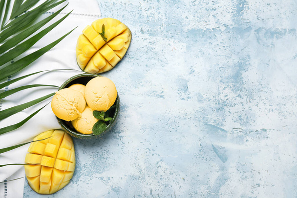 Bowl with tasty mango ice cream and palm leaf on color background - Foto, imagen