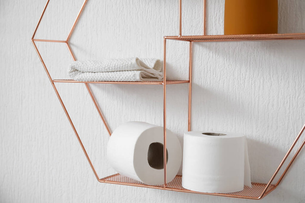 Shelf with rolls of toilet paper and towel hanging on light wall - Foto, immagini