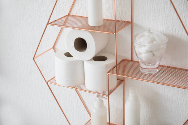 Полка с рулонами туалетной бумаги и принадлежностями для ванн висит на светлой стене - Фото, изображение
