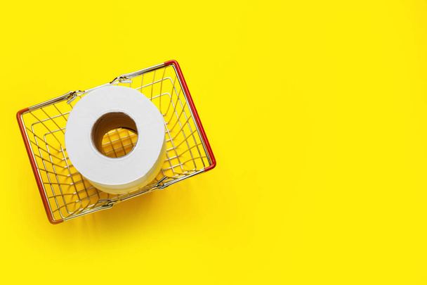 Shopping basket with roll of toilet paper on color background - Fotografie, Obrázek