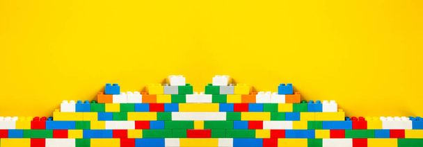 Plastic building blocks on yellow background - Photo, Image