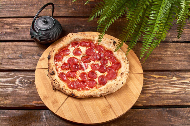 Pizza de pepperoni en un soporte de madera - Foto, Imagen