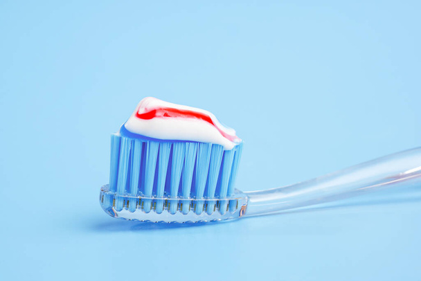 toothbrush with tricolor toothpaste on it on blue background - Φωτογραφία, εικόνα