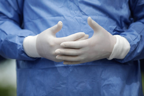 Szczegóły z rąk pracownika medycznego w rękawiczkach chirurgicznych gestykulujących podczas rozmowy. - Zdjęcie, obraz