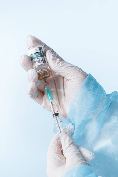 Geen LOGOS of TRADEMARKS! ZELF maakte etiketten! Bekijk van dichtbij de handen van artsen met een ampul van koel vaccin en spuit op blauwe rug - Foto, afbeelding