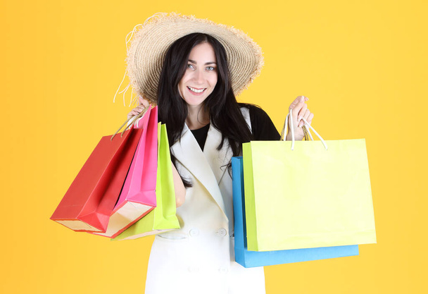 krásná žena jít na nákupy a držení tašky se žlutým pozadím - Fotografie, Obrázek