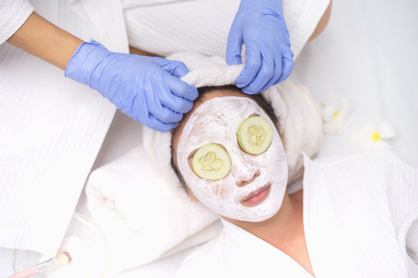 Junge Asiatinnen erhalten Gesichtspflege, Gesichtsmasken und Wellness-Schönheitsbehandlungen für weiche, seidige Haut. Hilft bei hausgemachter Gesichtsmaske mit Gurkenscheiben Augenmaske für müde Augen. - Foto, Bild