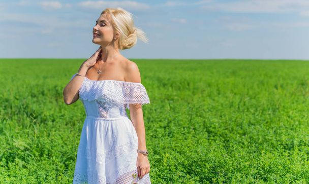 Vapauden käsite, romanttinen kuva naisesta vihreällä alalla, ilta aurinko, kauneus romanttinen tyttö valkoisessa mekossa Ulkona. Aurinko paistaa - Valokuva, kuva