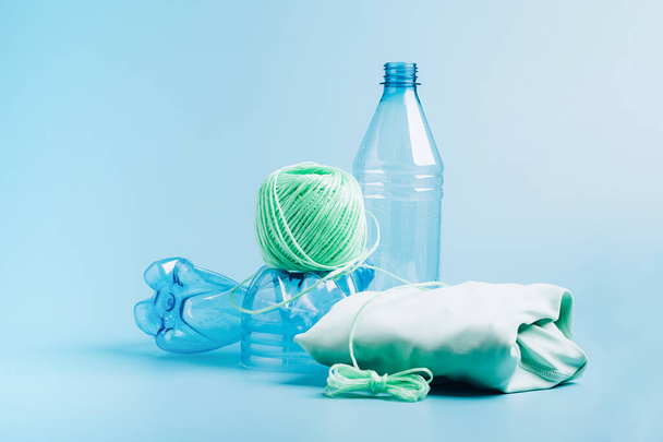Концепція переробки пластику. Порожня пластикова пляшка та перероблене поліефірне волокно, синій фон з синтетичної тканини
 - Фото, зображення