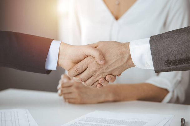 Business people shaking hands finishing contract signing in sunny office, close-up. Handshake and marketing - Foto, imagen
