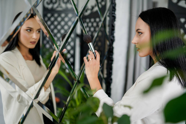 Young make-up artist with brushes in modern interior room with green plants - Foto, immagini