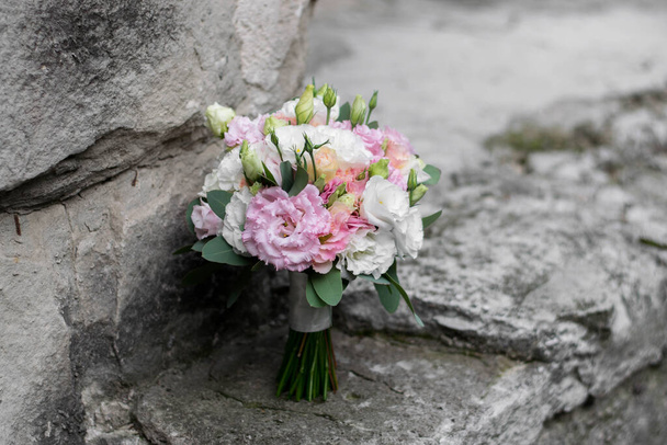 Beautiful bridal bouquet of white flowers and greenery, on a gray textural background. Wedding day. - Фото, изображение