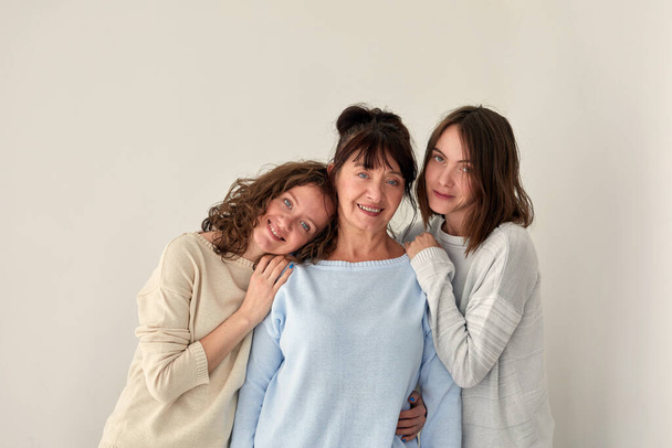 Smiling mother hugging daughters and looking at camera - Photo, Image