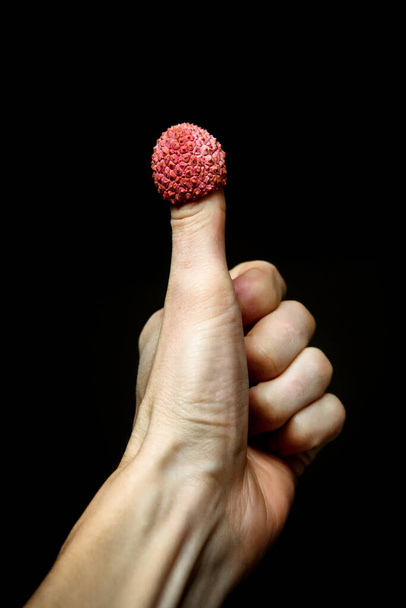 ok palec s liči, obrázek ruky s ovocem na černém pozadí - Fotografie, Obrázek