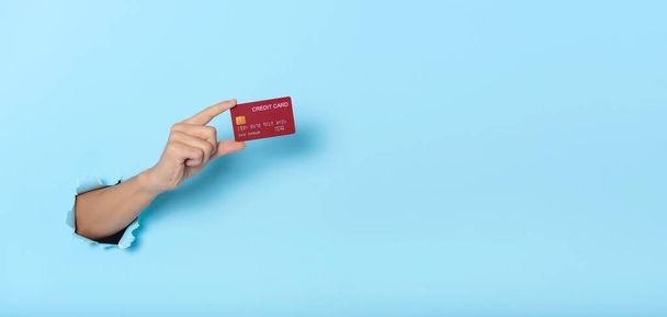 Woman hand holding credit card on blue banner background. Panoramic image - Zdjęcie, obraz