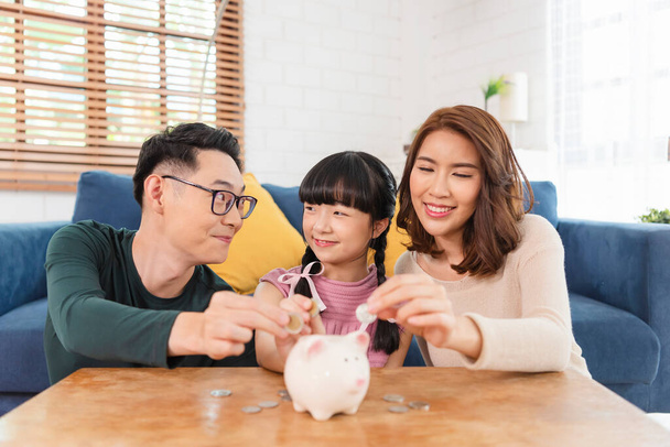 Boldog ázsiai család pénzt spórol a malacperselyben. beruházás a jövőbeli koncepcióba. - Fotó, kép