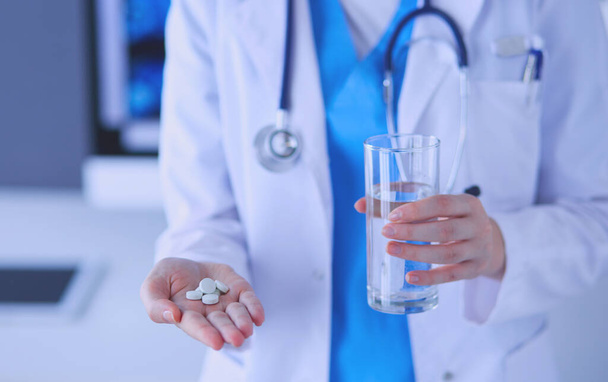Close-up shot of doctors hands holding pills and glass of water. - Фото, зображення
