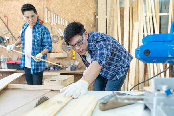 Artesanos trabajando juntos en carpintería. Carpintero trabajando con sierra circular en taller de carpintería. - Foto, Imagen