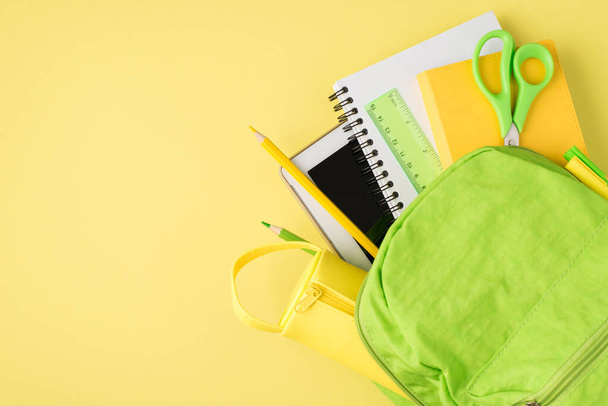 Above photo of backpack ruler notepad pen pencil tablet and pencil-box isolated on the yellow background - 写真・画像