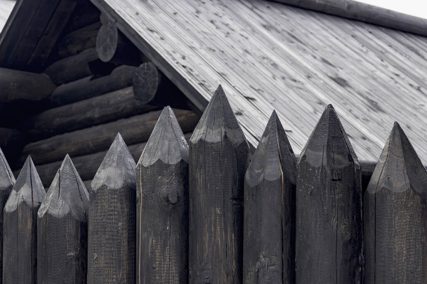 A protective fence made of logs with sharp upper ends, used in ancient Russia to protect against enemies. Traditional old Russian wooden construction of houses. - Photo, Image