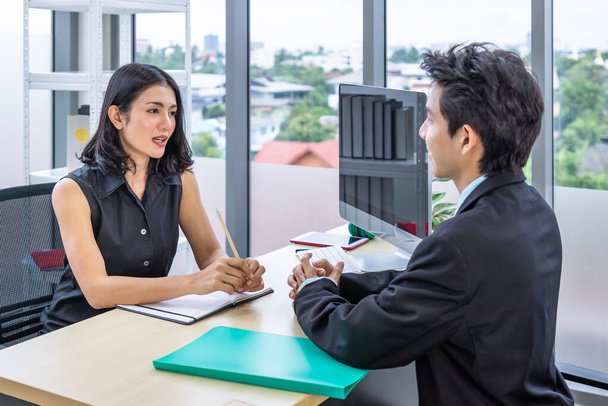Kobieta pracodawca rozmowa kwalifikacyjna młody mężczyzna osoba ubiegająca się o pracę na wakat biznesowy siedzi w biurze. - Zdjęcie, obraz