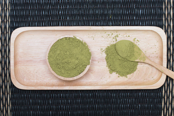 Порошковий зелений чай на дерев'яному підносі, розміщеному на килимку
. - Фото, зображення