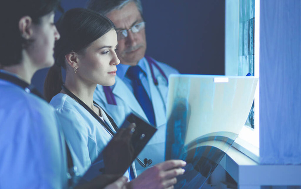 Groep artsen die röntgenfoto 's in een kliniek onderzoeken, denken aan een diagnose - Foto, afbeelding