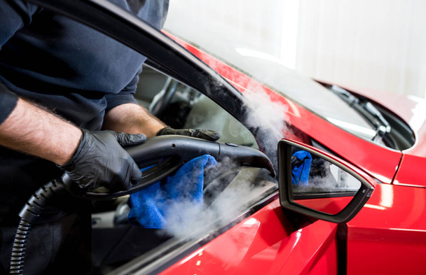Car service worker cleans interiror with steam cleaner - Foto, Bild