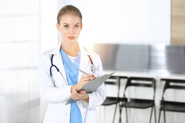 Woman - doctor is using clipboard for filling up medication history record in clinic. Medicine concept - Foto, Imagen