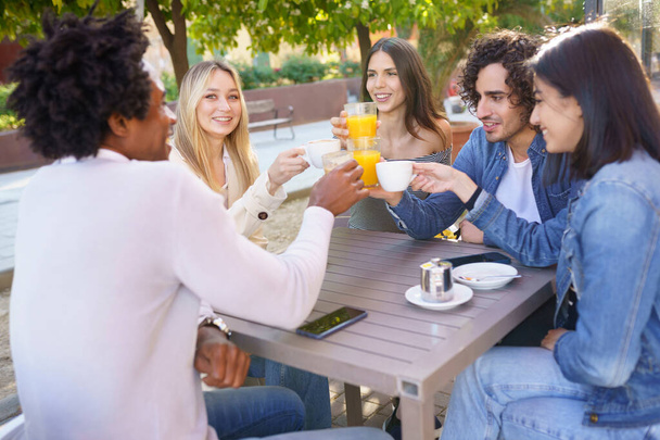 Grupo multiétnico de amigos brindando con sus bebidas mientras toman una copa juntos. - Foto, Imagen