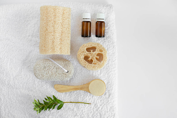beauty flatley for personal care. loofah, glass bottles, pumice stone, loofah, face wash, comb on a white towel - Photo, Image