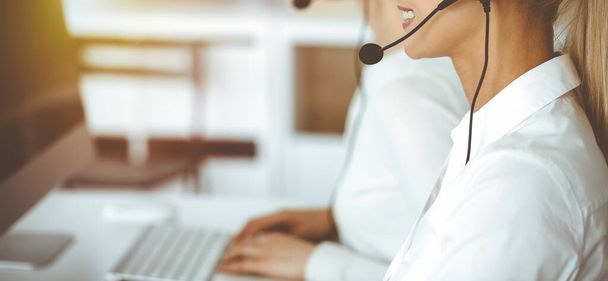 Unknown female customer service representative iconsulting clients online using headset.close-up. Sunny Call center - Φωτογραφία, εικόνα