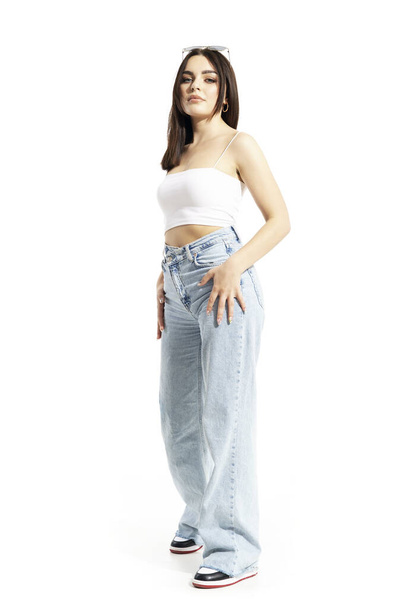 Self assicurato trendy bella donna in posa in jeans e scarpe da ginnastica. Lunghezza totale del corpo isolata su sfondo bianco - Foto, immagini