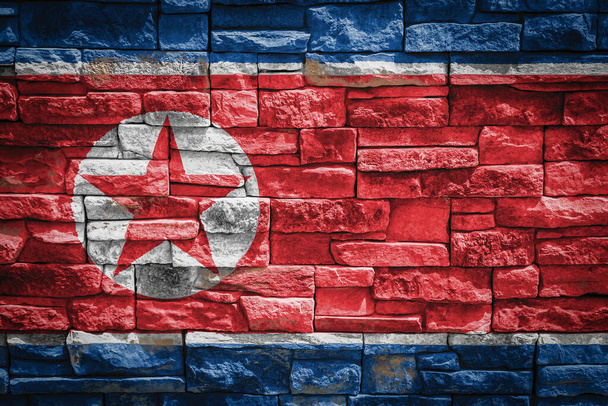 石壁の背景に北朝鮮の国旗国家の誇りと国のシンボルの概念。石の質感の背景に旗. - 写真・画像