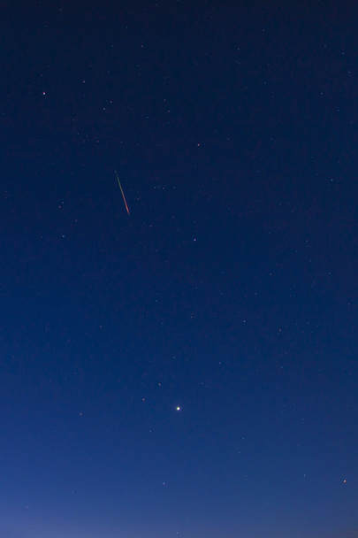 Jasnoczerwono-zielony meteoryt przepływu Perseidów na nocnym niebie - Zdjęcie, obraz