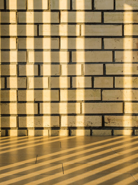 Ombre horizontale rayée sur un mur de briques jaunes. Rayons de soleil lisses et horizontaux. Texture inhabituelle - Photo, image