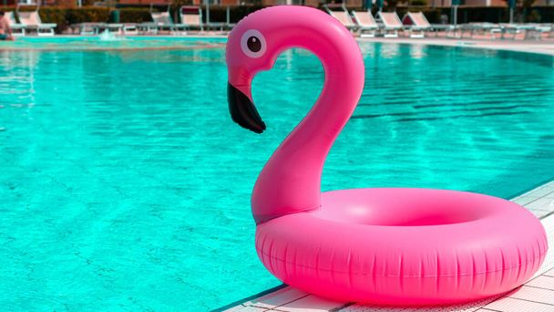 Zomertijd. Roze opblaasbare flamingo in zwembadwater voor zomerse strand achtergrond. Grappig vogelspeelgoed voor kinderen - Foto, afbeelding