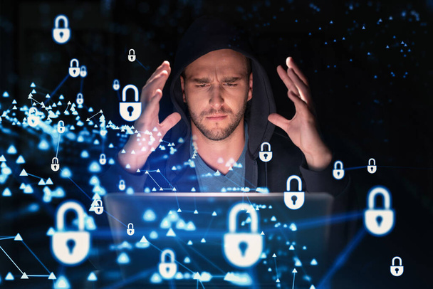 Handsome businessman in hoodie at workplace working with laptop to defend customer cyber security. Concept of clients information protection and brainstorm. Padlock hologram over office background - Fotoğraf, Görsel