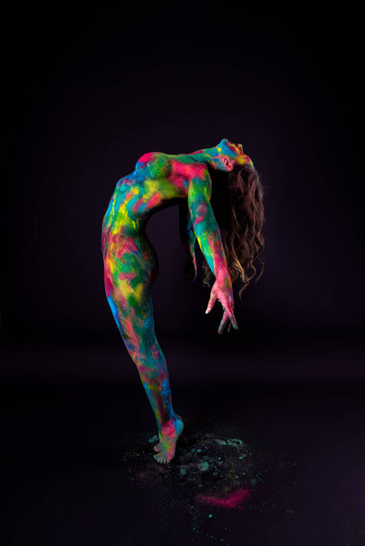 Bright colorful body art on black background, sexy nude woman painted with powder paints, studio shot - Photo, Image