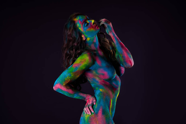 Bright colorful body art on black background, sexy nude woman painted with powder paints, studio shot - Foto, afbeelding