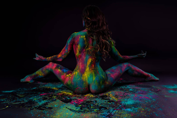 Bright colorful body art on black background, sexy nude woman painted with powder paints, studio shot - Valokuva, kuva