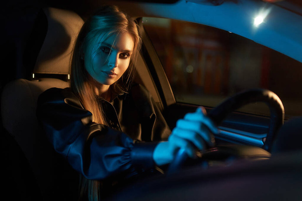 Beautiful young woman driving car at night - Foto, afbeelding