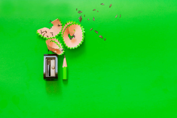 A short green pencil sharpened with a sharpener, shavings on a green background. - 写真・画像