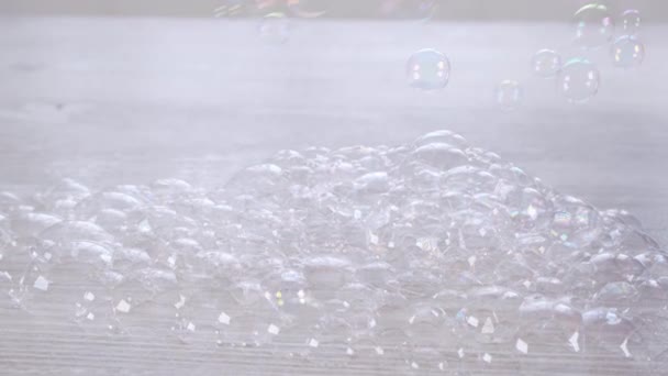 Burbujas de jabón arco iris en una mesa de madera blanca. Concepto de relajación e imaginación, infancia - Metraje, vídeo