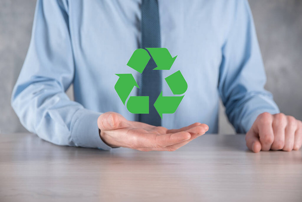Empresario en traje sobre fondo oscuro sostiene un icono de reciclaje, firmar en sus manos. Ecología, medio ambiente y concepto de conservación. Luz azul rojo neón. - Foto, imagen