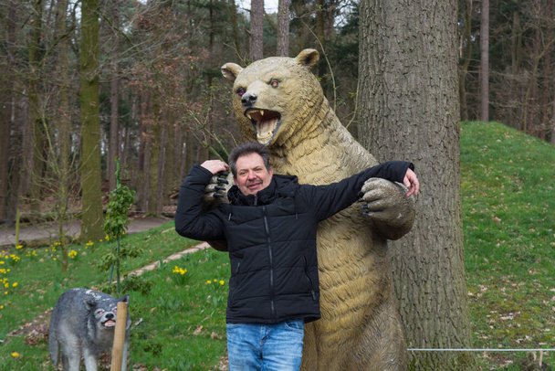 Mann in den Armen eines Braunbären. Das Thema Freundschaft zwischen Mensch und Tier.  - Foto, Bild